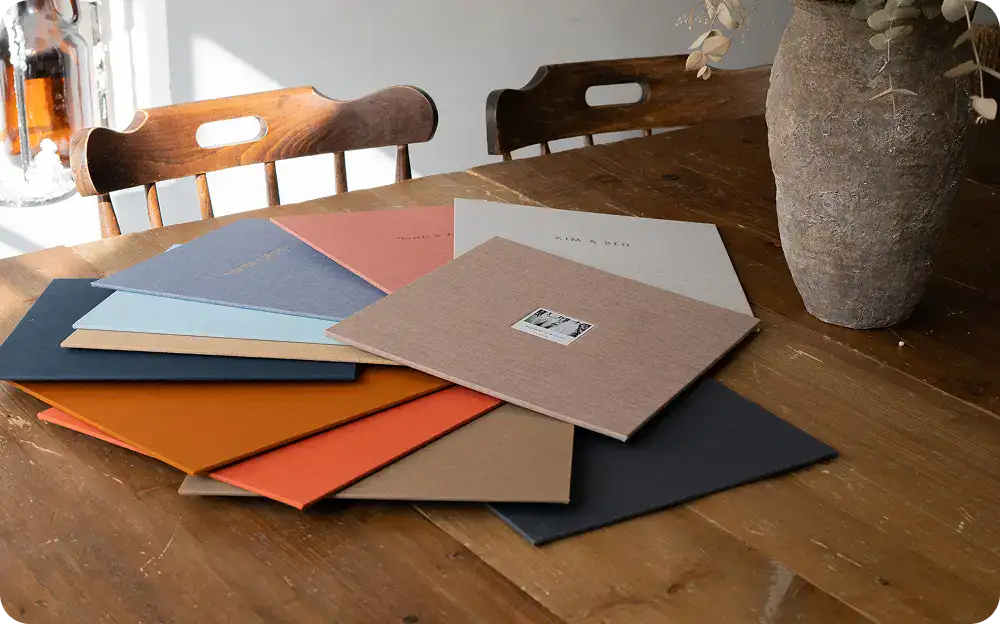 Assorted colorful paper samples on a wooden table for creative projects.