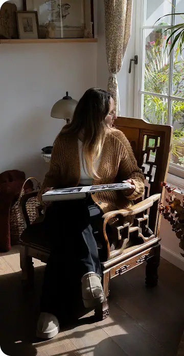 Elegant woman reading by window in cozy room.