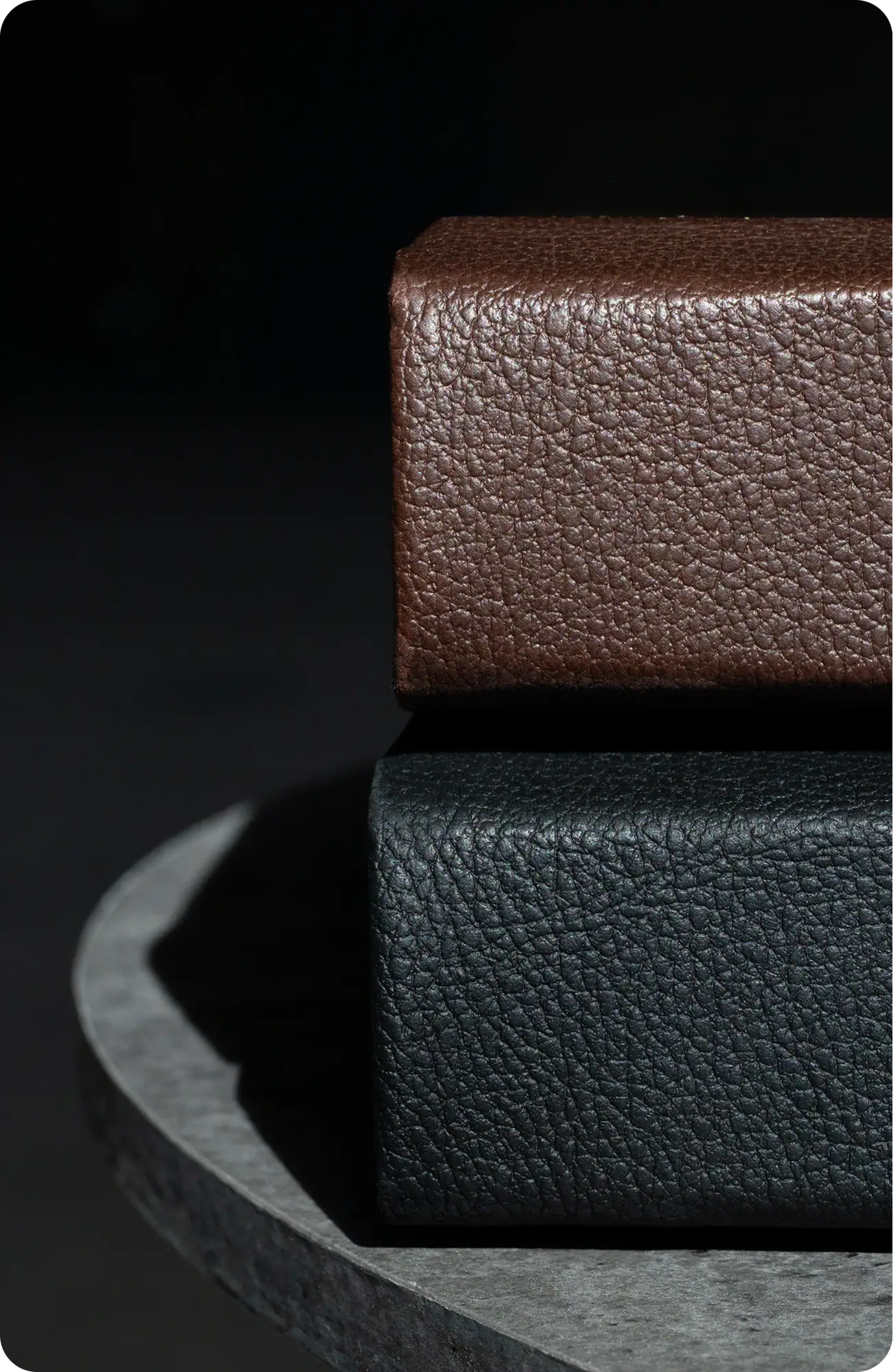 Close-up of brown and black textured binding materials stacked on a dark surface.