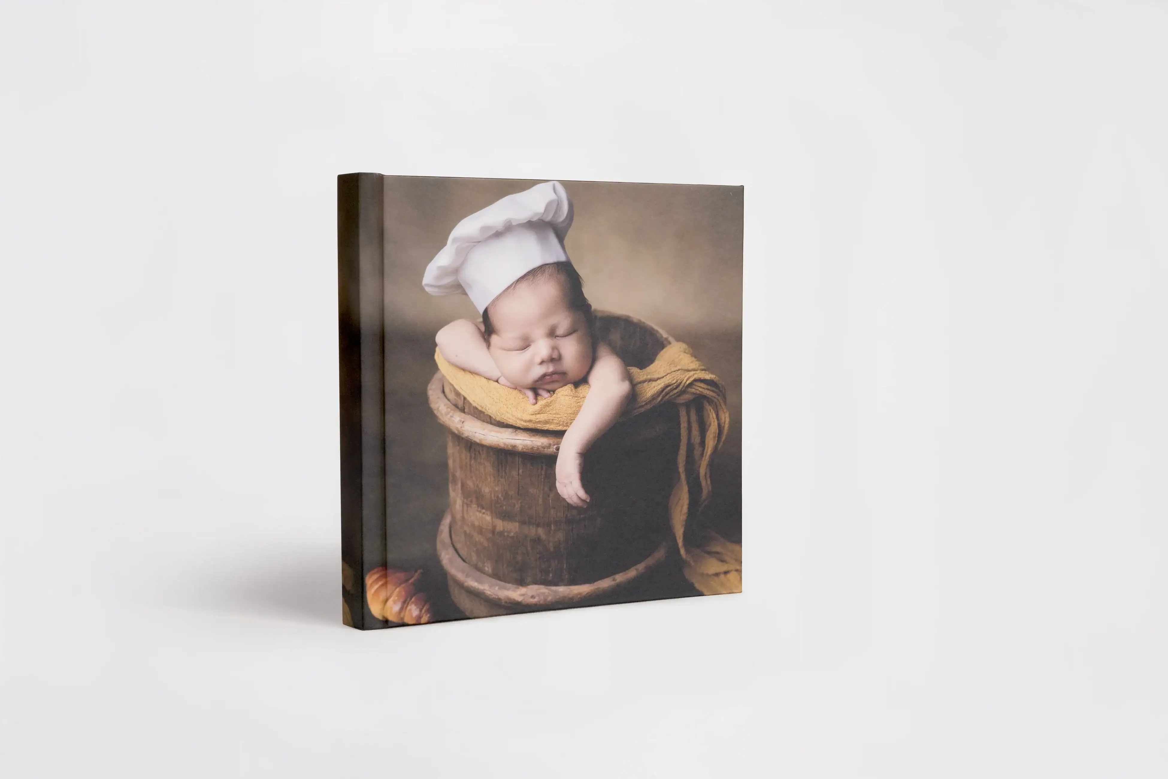 Adorable sleeping baby in a chef hat on a rustic background for New Born album.