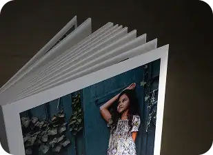 Wedding photo album on wooden table with candles and plant.