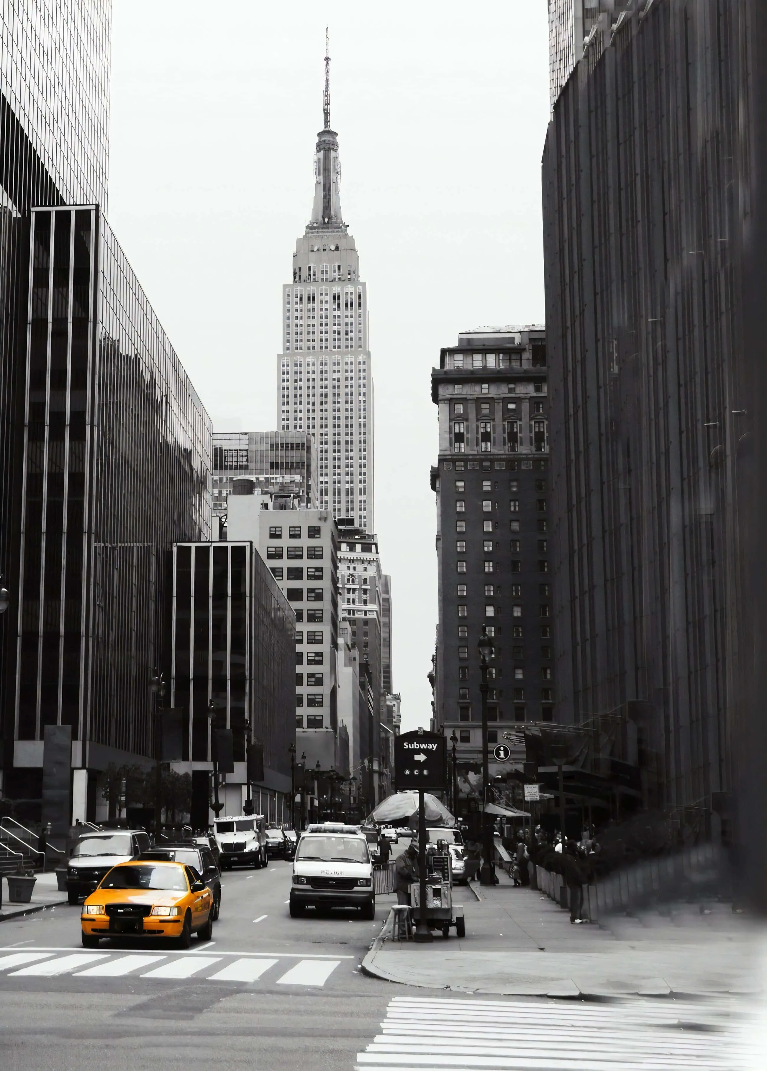 Black and white photo of New York City street with Empire State Building in background.